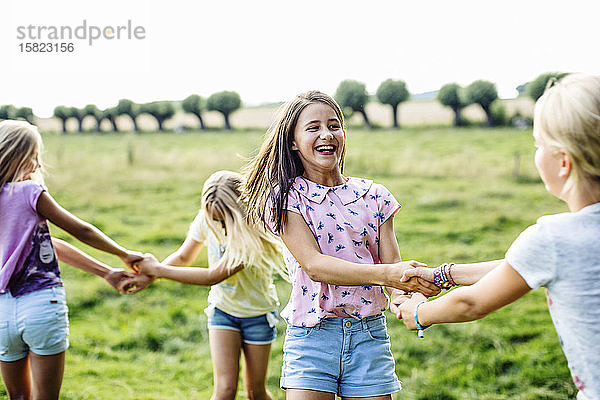 Glückliche Mädchen tanzen gemeinsam auf einem Feld