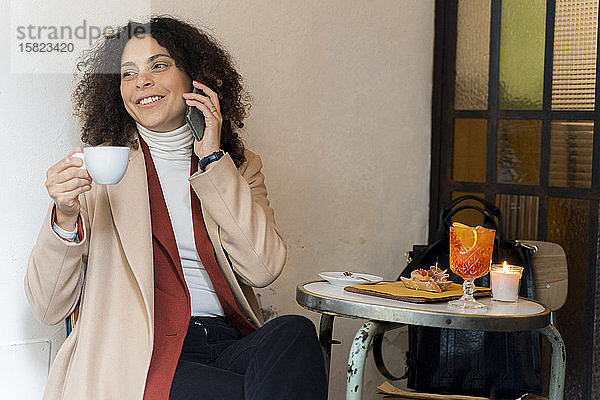 Lächelnde Frau am Telefon in einem Cafe