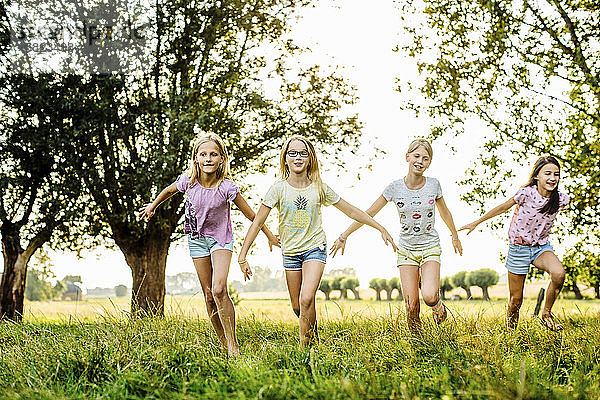 Glückliche Mädchen laufen auf einem Feld auf dem Land