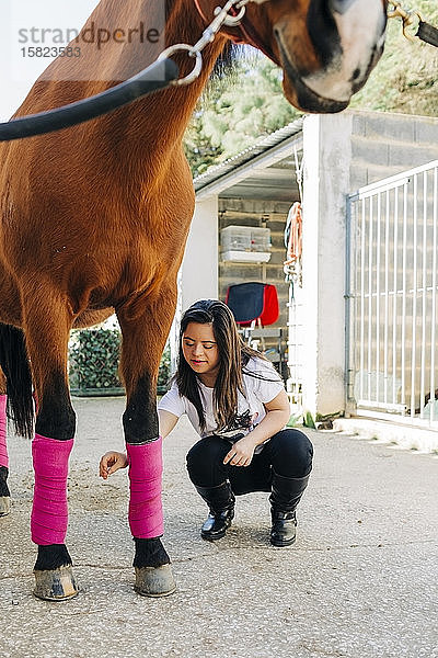 Teenager mit Down-Syndrom kümmert sich um Pferd und bereitet Pferd zum Reiten vor