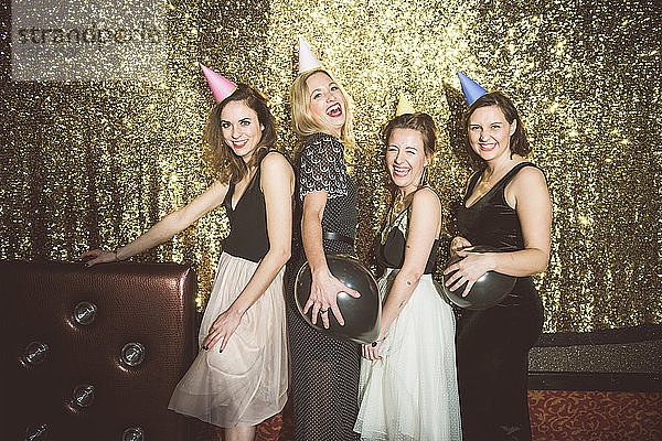 Porträt von vier glücklichen Frauen mit Partyhüten in einem Club