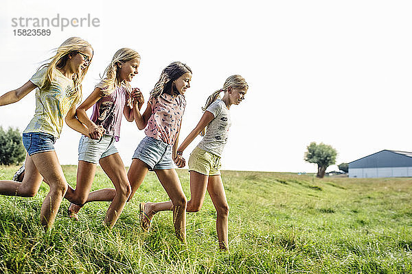 Glückliche Mädchen laufen auf einem Feld auf dem Land