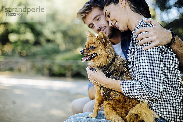 Glückliches junges Paar mit Hund in einem Park