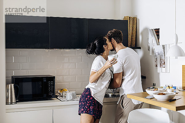 Zärtliches junges Paar am Morgen in der Küche