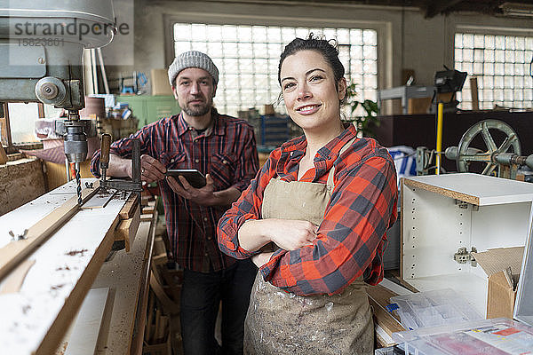 Porträt einer selbstbewussten Handwerkerin und eines Handwerkers in ihrer Werkstatt