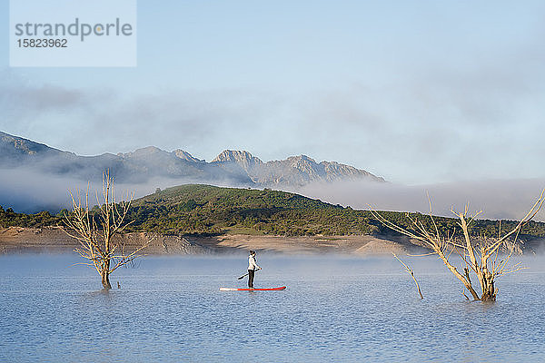 Frau steht beim Paddel-Surfen auf einem See auf
