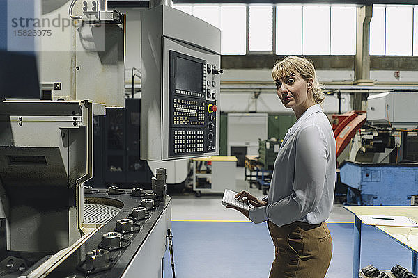 Porträt einer selbstbewussten Geschäftsfrau mit drahtloser Tastatur in einer Fabrik