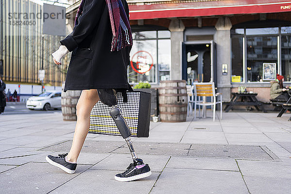 Niedriger Anteil einer Frau mit Beinprothese beim Gehen in der Stadt