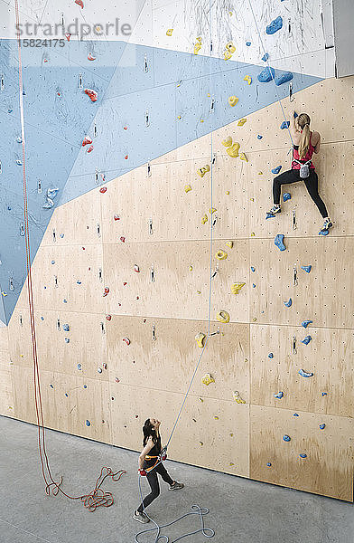 Frau mit einem Seilsicherungspartner an der Wand in der Kletterhalle