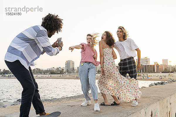 Glückliche Freunde posieren an der Kaimauer und machen ein Foto