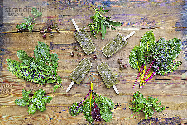 Draufsicht auf hausgemachtes grünes Gemüse und Kräuter-Eis am Holztisch