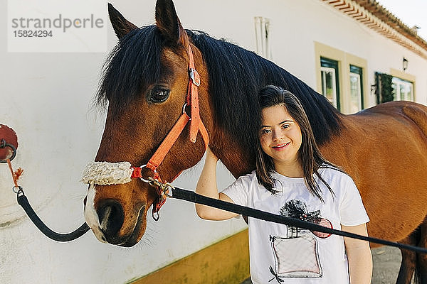 Teenager mit Down-Syndrom kümmert sich um Pferd und bereitet Pferd zum Reiten vor