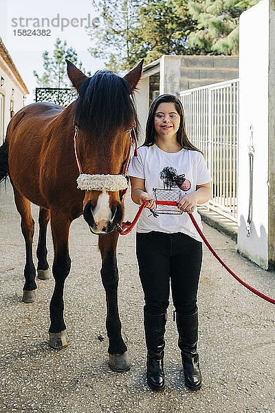 Teenager mit Down-Syndrom kümmert sich um Pferd und bereitet Pferd zum Reiten vor