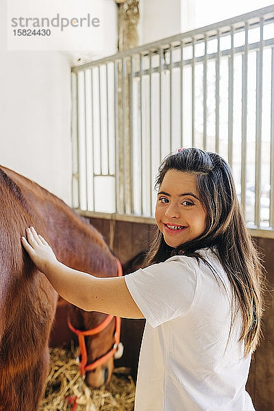 Teenager mit Down-Syndrom kümmert sich um Pferd und bereitet Pferd zum Reiten vor