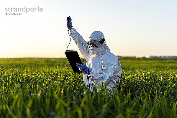 Wissenschaftlerin  die im Feld forscht und Messgeräte benutzt