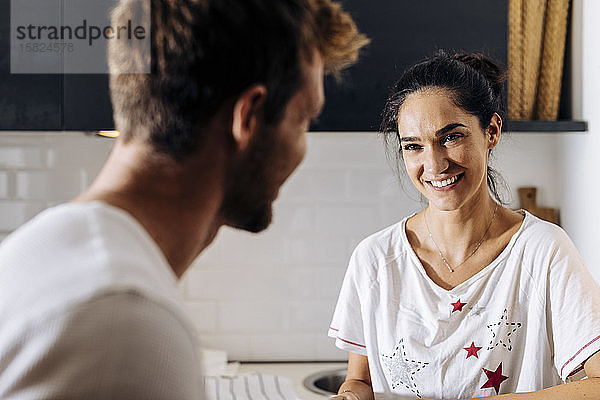 Porträt einer jungen Frau  die ihren Freund in der Küche anlächelt