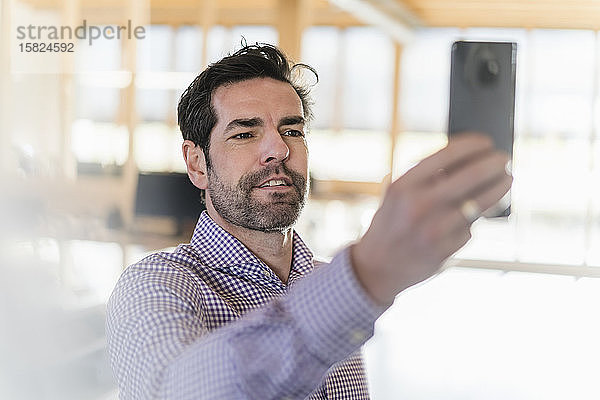Geschäftsmann beim Selfie im hölzernen Großraumbüro