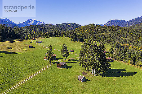 Deutschland  Bayern  Krun  Drohnenansicht von Hütten am Rande des Frühlingswaldes mit dem Wettersteingebirge im Hintergrund