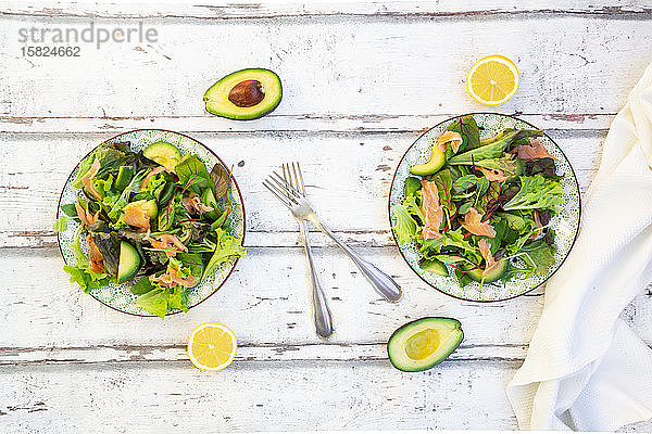 Zwei Teller verzehrfertiger grüner Salat mit Rucola  Lollo Rosso-Salat  Babyspinat  Rote-Bete-Blättern  Avocado  Feldsalat und Lachs