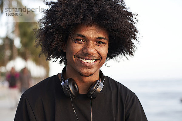 Porträt eines lächelnden jungen Mannes mit Kopfhörern  der in die Kamera schaut