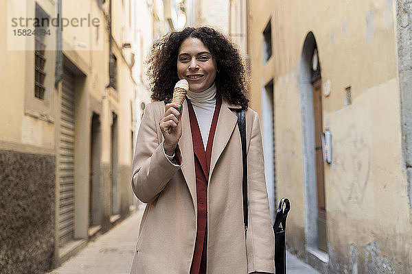 Porträt einer lächelnden Frau  die in einer Gasse eine Eistüte isst  Florenz  Italien