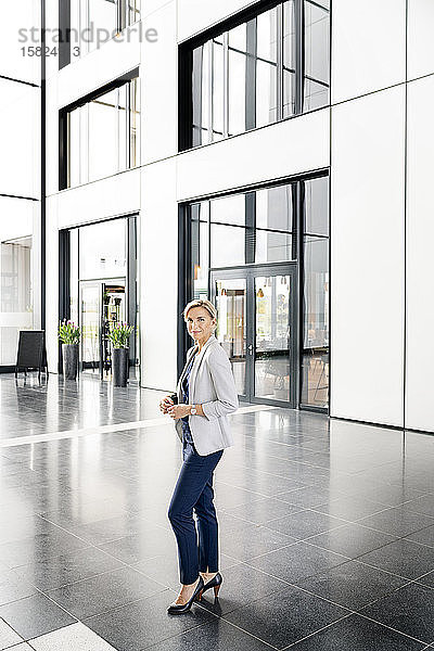 Erfolgreiche Geschäftsfrau steht in der Eingangshalle eines Bürogebäudes
