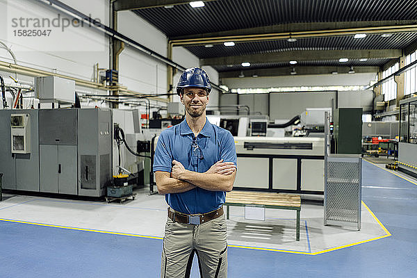 Porträt eines selbstbewussten Arbeiters in einer Fabrik mit Schutzhelm