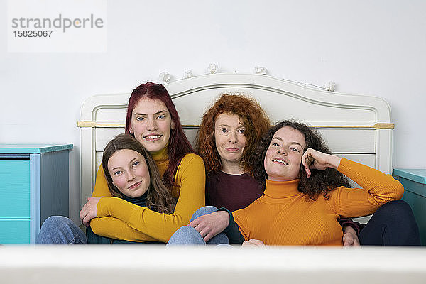 Porträt der Mutter und ihrer drei Töchter  die zusammen auf dem Bett sitzen