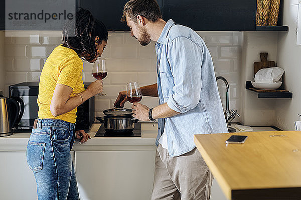 Junges Paar kocht und trinkt zu Hause gemeinsam Wein in der Küche