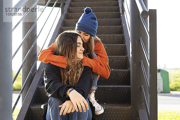 Zwei Mädchen im Teenageralter sitzen auf einer Treppe im Freien