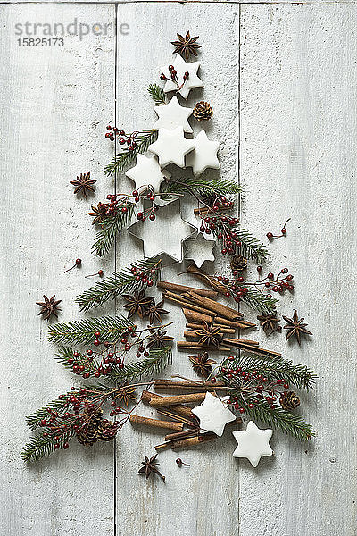 Sternförmige Kekse  Zimtstangen  Tannenzweige  Sternanis  Keksausstecher  Tannenzapfen und Hagebutten in Form eines Weihnachtsbaums