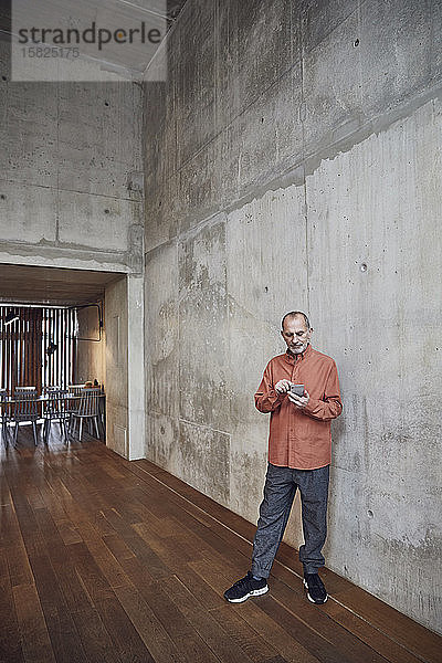 Kreativer Geschäftsmann mit Smartphone in seinem minimalistischen Büro