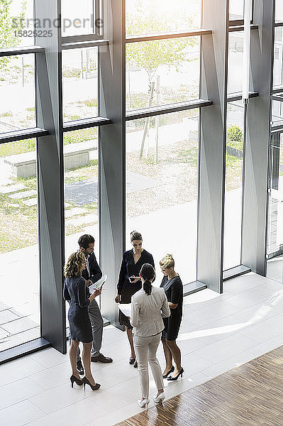 Geschäftsleute stehen in modernem Bürogebäude und diskutieren Projekt