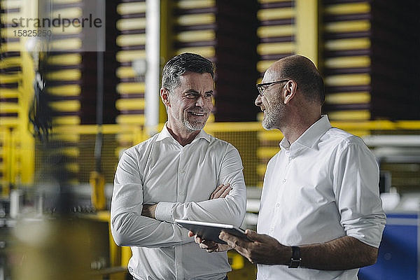 Zwei Geschäftsleute verwenden Tabletten in einer Fabrik