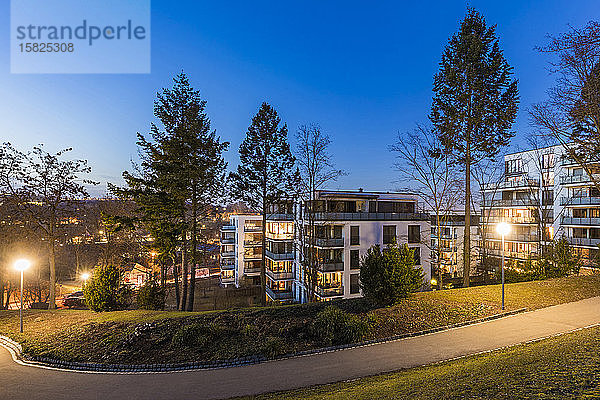Deutschland  Baden-Württemberg  Stuttgart  Leerer Fußweg im öffentlichen Park in der Dämmerung mit modernen Wohnungen im Hintergrund