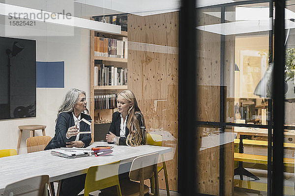 Reife und junge Geschäftsfrau untersucht Architekturmodell im Loft-Büro