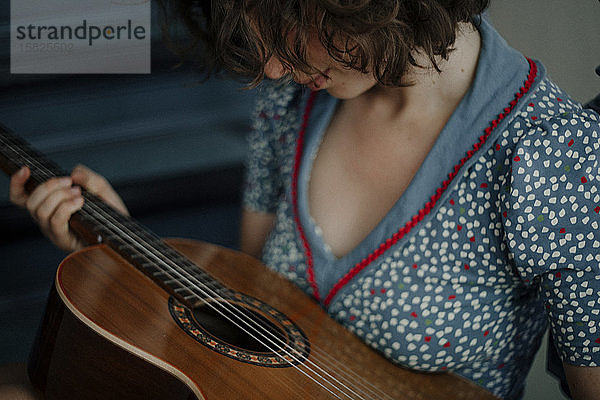 Schrägansicht einer jungen Frau mit Gitarre