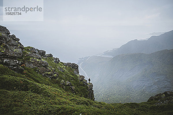 Norwegen  Lofoten  Reine  Mann betrachtet Aussicht vom Berg ReinebringenÂ bei Regen