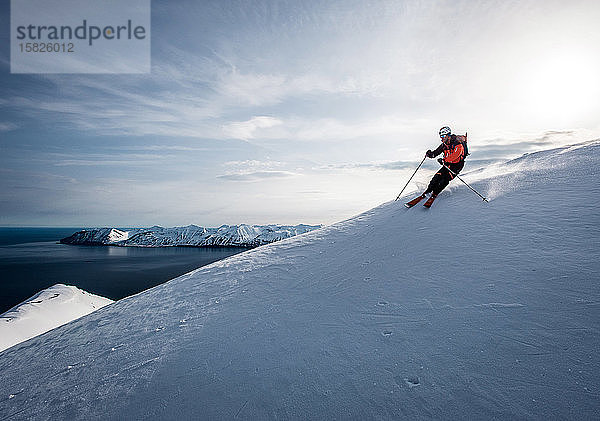 Ein Mann auf Skiern mit Ozean im Hintergrund in Island