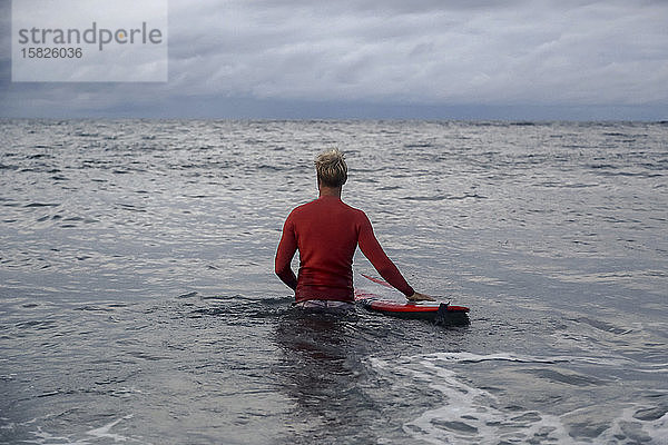 Mann mit Surfbrett auf dem Meer