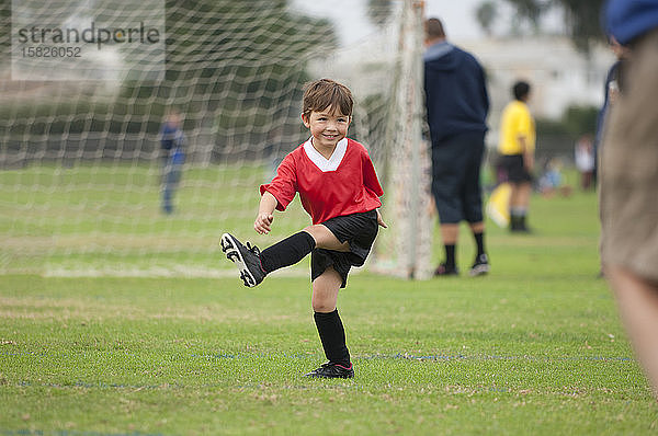Junge mit großem Lächeln beim Treten eines imaginären Fußballs