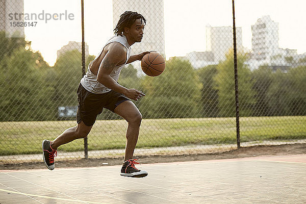 Afroamerikanischer Mann spielt Basketball im Freien