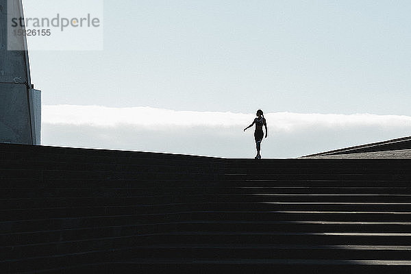 Silhouette einer Frau  die auf einer Treppe geht  mit blauem Himmel im Hintergrund