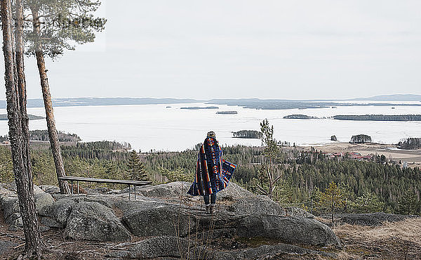 Frau  die auf einem Felsen steht und die schöne Aussicht in Schweden genießt