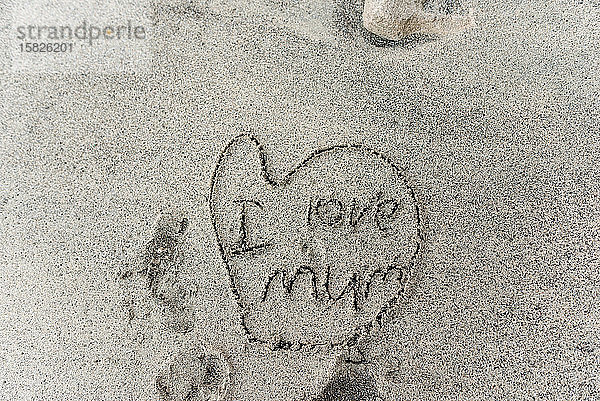 Kinderzeichnung im Sand des Herzens mit der Aufschrift Ich liebe Mama
