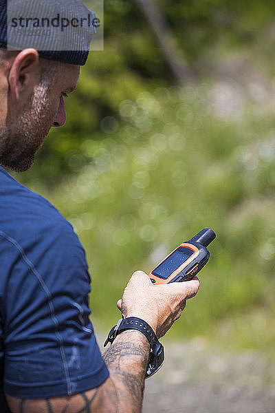 Mann navigiert beim Wandern mit einem GPS-Gerät