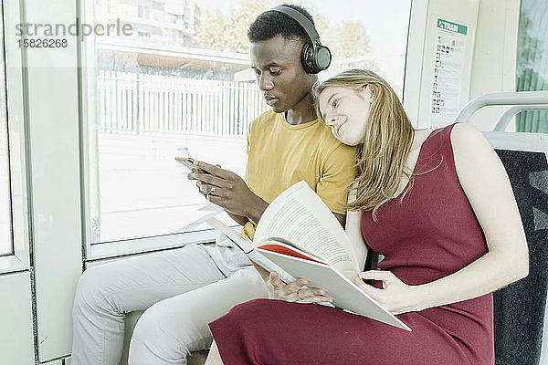 Mädchen liest und Junge hört Musik im Bus