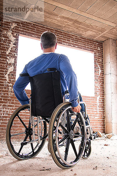 Ein Mann im Rollstuhl in einem im Bau befindlichen Haus mit Blick nach draußen