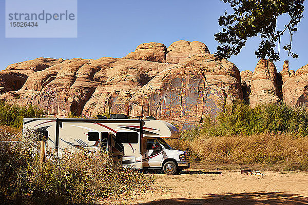 Ein Wohnmobil parkt vor einer roten Felswand in Moab  Utah.