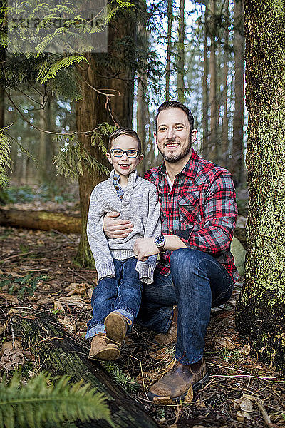 Der junge Vater hält seinen hübschen Sohn im Wald.